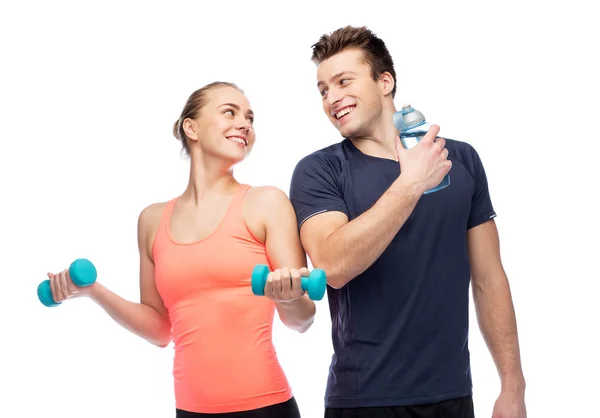 Hombre y mujer deportivos con mancuerna y agua — Foto de Stock