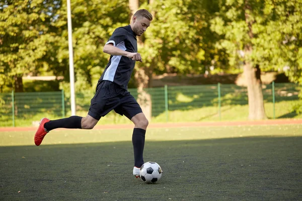 Fußballer spielt mit Ball auf Fußballplatz Stockbild
