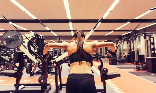 Mulher flexionando músculos na máquina de cabo no ginásio — Fotografia de Stock