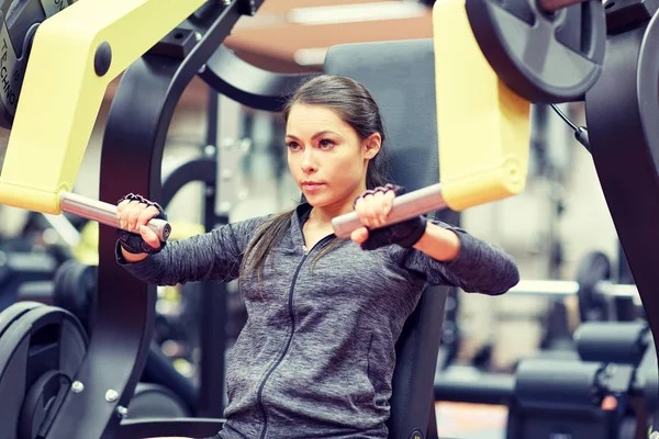 Mujer flexionar los músculos en la máquina de gimnasio de prensa de pecho —  Fotos de Stock