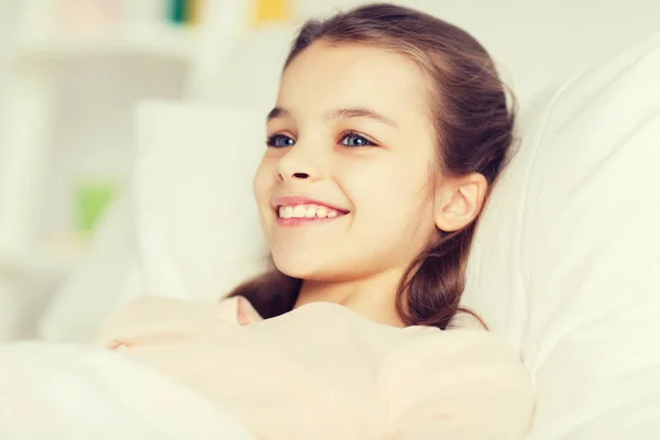 Glücklich lächelndes Mädchen, das zu Hause wach im Bett liegt — Stockfoto