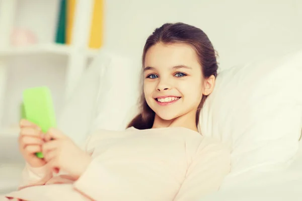 Mutlu kız ile smartphone evde yatakta yalan — Stok fotoğraf