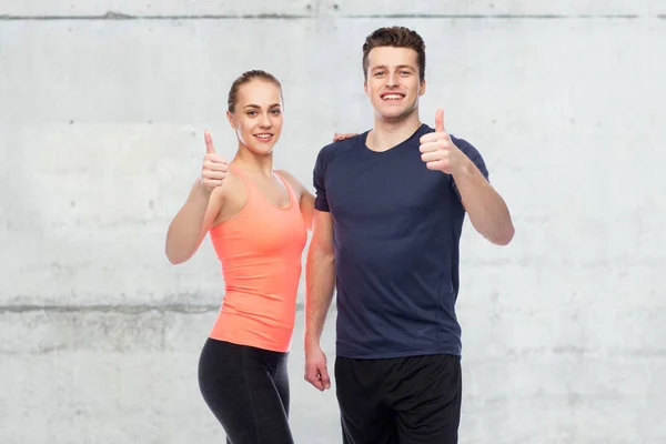 Feliz deportivo hombre y mujer mostrando los pulgares hacia arriba —  Fotos de Stock