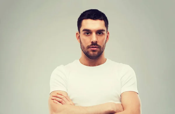 Jeune homme avec les bras croisés sur fond gris — Photo