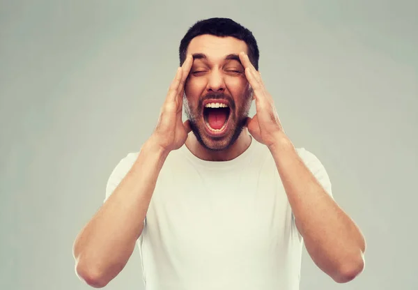Loco gritando hombre en camiseta sobre fondo gris — Foto de Stock