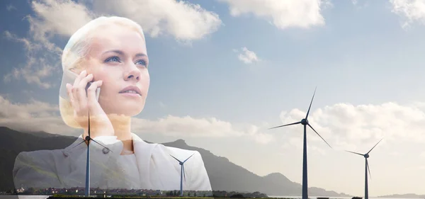 Деловая женщина со смартфоном над ветряными турбинами — стоковое фото