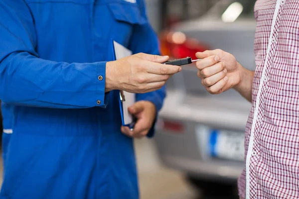 Automechaniker übergibt Mann Autoschlüssel in Werkstatt — Stockfoto