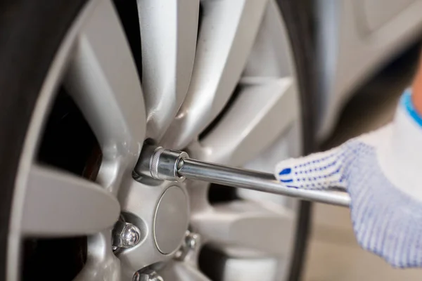 Mecânico com chave de fenda trocando pneu do carro — Fotografia de Stock