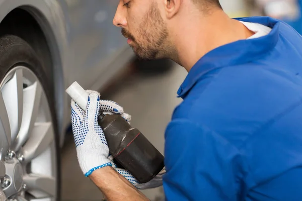 Mechanic with screwdriver changing car tire — Stock Photo, Image