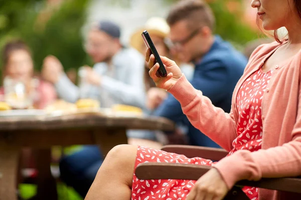 Женщина со смартфоном и друзьями на летней вечеринке — стоковое фото