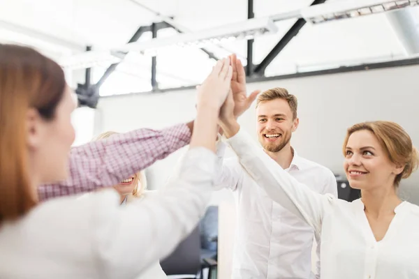 Glada affärsteam gör high five på kontoret — Stockfoto