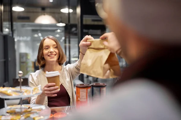 Mujer tomando bolsa de papel del vendedor en la cafetería — Foto de Stock
