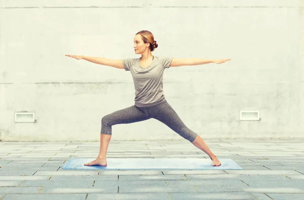 Женщина делает воин yoga поза на циновке — стоковое фото