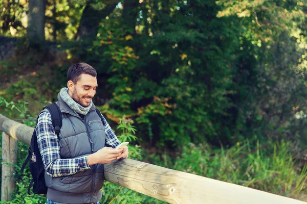 Lycklig man med ryggsäck och smartphone utomhus — Stockfoto