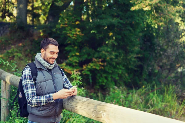 Homem feliz com mochila e smartphone ao ar livre — Fotografia de Stock