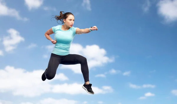 Sportig kvinna hoppa i striderna pose över himlen — Stockfoto
