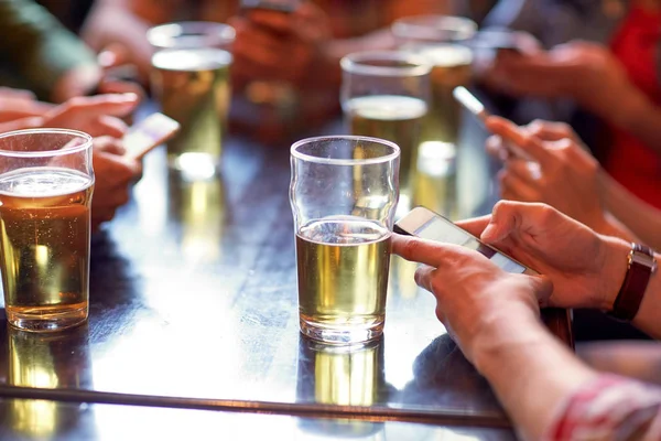 Друзья с пивом и смартфонами в баре или пабе — стоковое фото