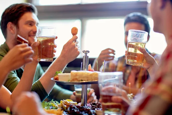 Щасливі друзі їдять і п'ють в барі або пабі — стокове фото