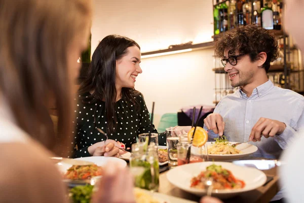 Щасливі друзі їдять і п'ють в ресторані — стокове фото