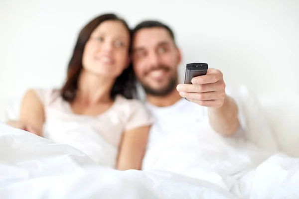 Feliz casal deitado na cama em casa e assistindo tv — Fotografia de Stock