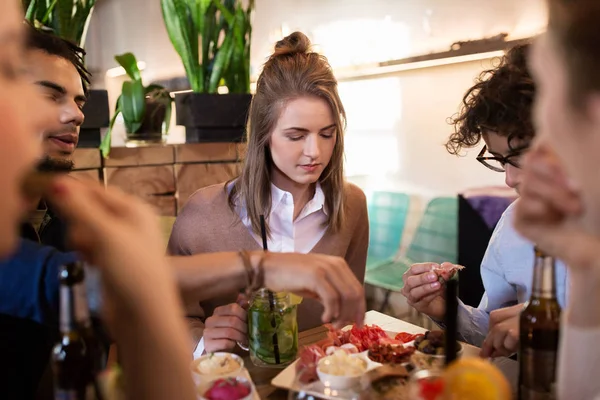 Счастливые друзья едят и пьют в баре или кафе — стоковое фото
