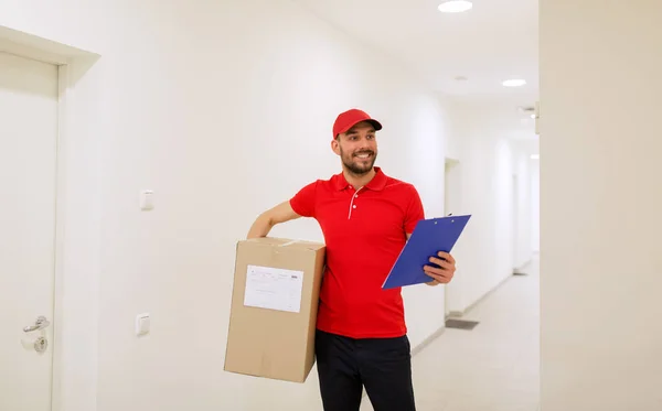 Repartidor con caja y portapapeles en pasillo — Foto de Stock