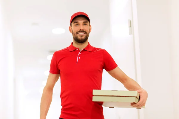 Happy delivery man with pizza boxes in corridor — Stock Photo, Image