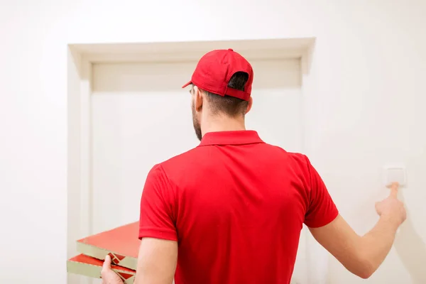 Delivery man with pizza boxes ringing doorbell — Stock Photo, Image