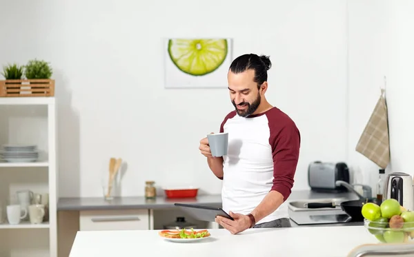 Hombre con tableta PC comer en casa cocina —  Fotos de Stock