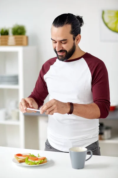 Uomo fotografare il cibo da smartphone a casa — Foto Stock