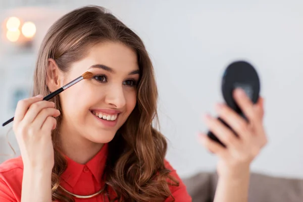 Kvinna med ögonskugga borste och spegel gör makeup — Stockfoto