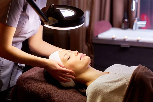Kosmetyczka robi masaż twarzy kobiecie w spa — Zdjęcie stockowe