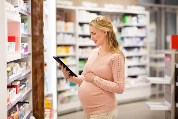 Mujer embarazada feliz con la tableta PC en la farmacia —  Fotos de Stock