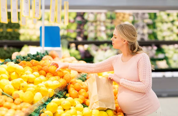 Schwangere mit Tüte kauft Orangen im Supermarkt — Stockfoto
