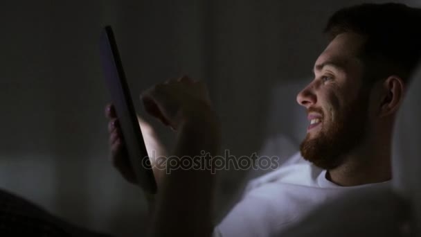 Tablet pc ev yatak odası, yatakta ile genç adam — Stok video