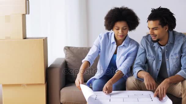 Feliz pareja con plano y cajas en el nuevo hogar — Vídeo de stock