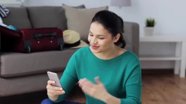 Vrouw met smartphone en reizen spullen thuis — Stockvideo