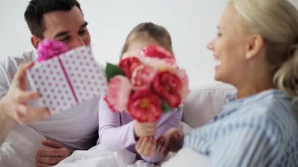 Família dando flores e presente para a mãe na cama — Vídeo de Stock