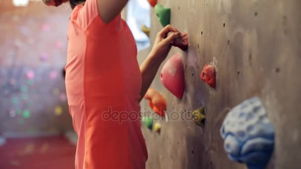 Jovem mulher exercitando na parede do ginásio de escalada interior — Vídeo de Stock