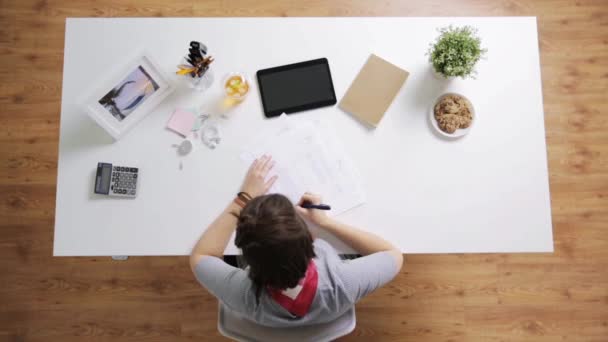 Frau mit Papieren und Taschenrechner im Homeoffice — Stockvideo