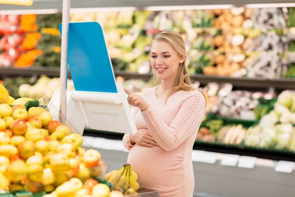 Kobieta w ciąży z bananami na skali w grocery — Zdjęcie stockowe