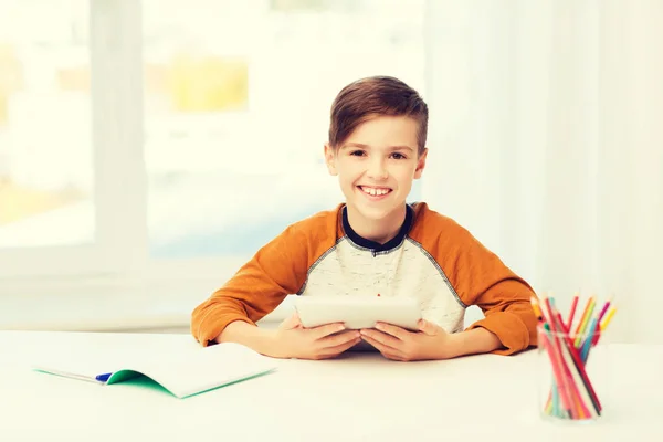 Menino sorridente com tablet pc e notebook em casa — Fotografia de Stock