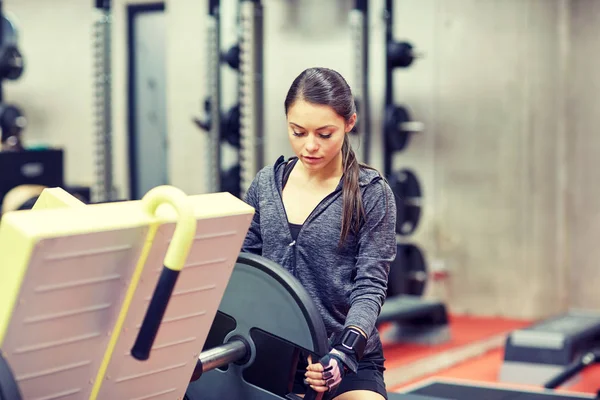 Genç kadın ayarlama bacak basın makine spor salonunda — Stok fotoğraf