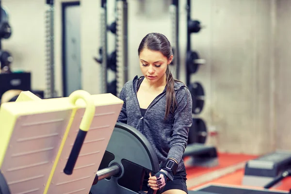 Mujer joven ajustando la máquina de prensa de piernas en el gimnasio —  Fotos de Stock