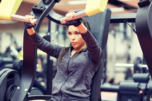 Femme flexion muscles sur poitrine presse gymnase machine — Photo