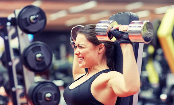Mujer joven flexionando músculos con mancuerna en el gimnasio — Foto de Stock