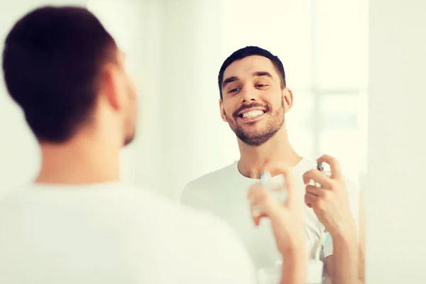 Muž s parfémy při pohledu do zrcadla v koupelně — Stock fotografie
