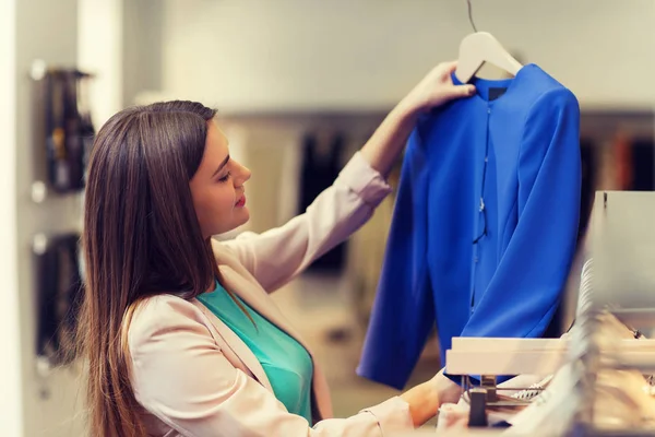 Feliz joven mujer elegir ropa en el centro comercial — Foto de Stock