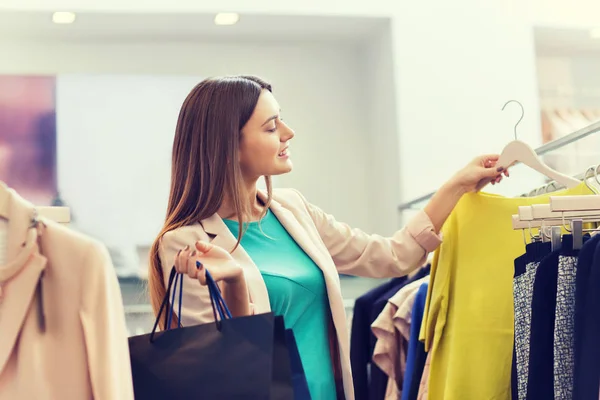 Gelukkig jonge vrouw kleding in winkelcentrum kiezen — Stockfoto