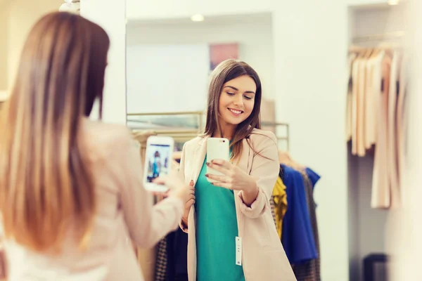 Женщина делает зеркальное селфи на смартфоне в магазине — стоковое фото